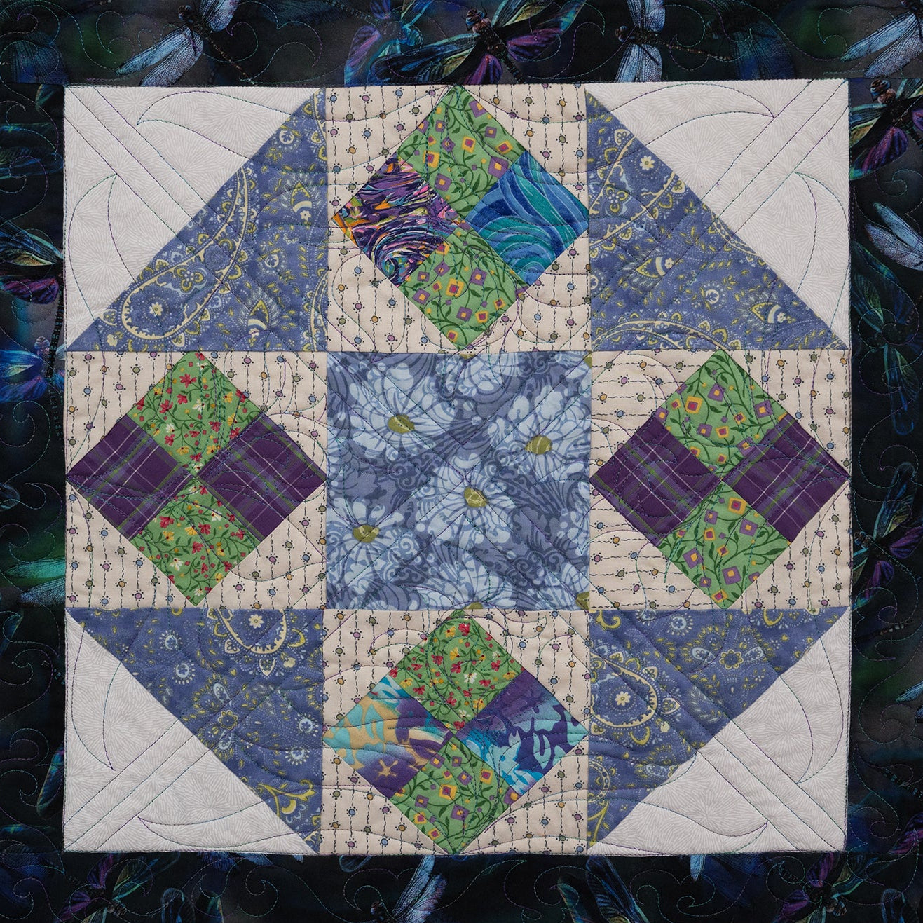 Quilt block with diamond pattern in blue, green, and purple on a dark background