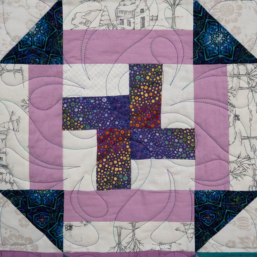 Quilt with geometric pattern featuring purple, blue, and pink colors on a white background.