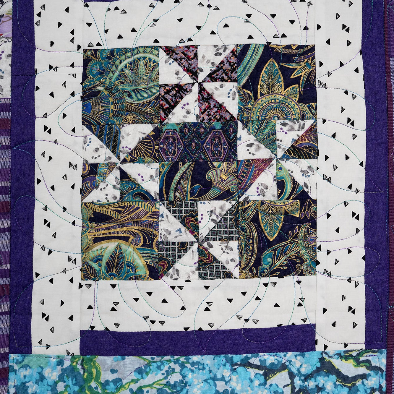 Quilt with a pattern of squares and triangles in various colors.