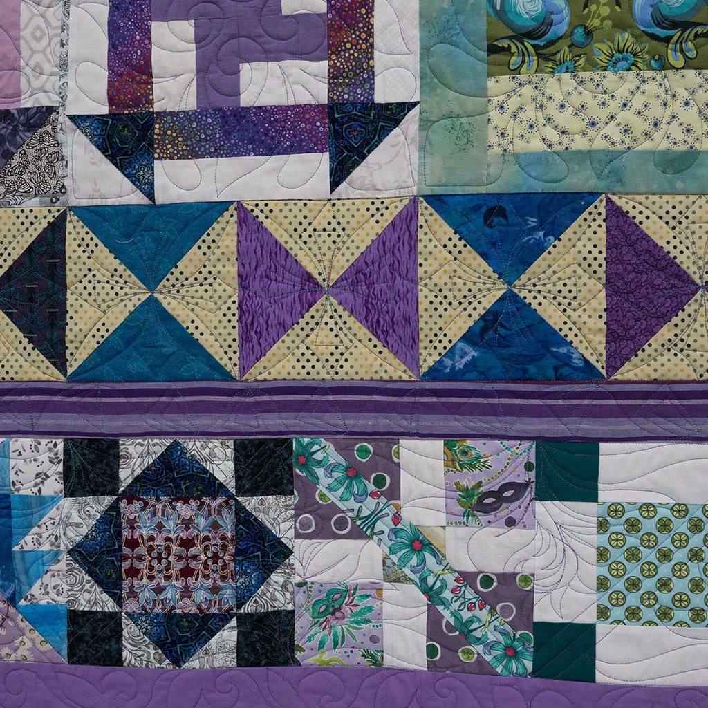 Quilt with geometric patterns in purple, blue, and green