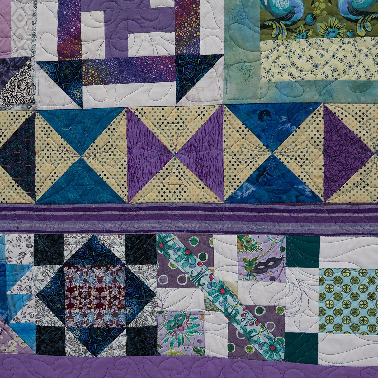 Quilt with geometric patterns in purple, blue, and green