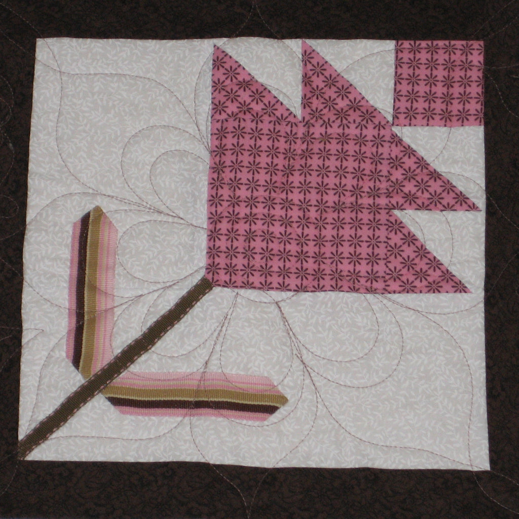 Quilt block with a flower shape in pink and brown