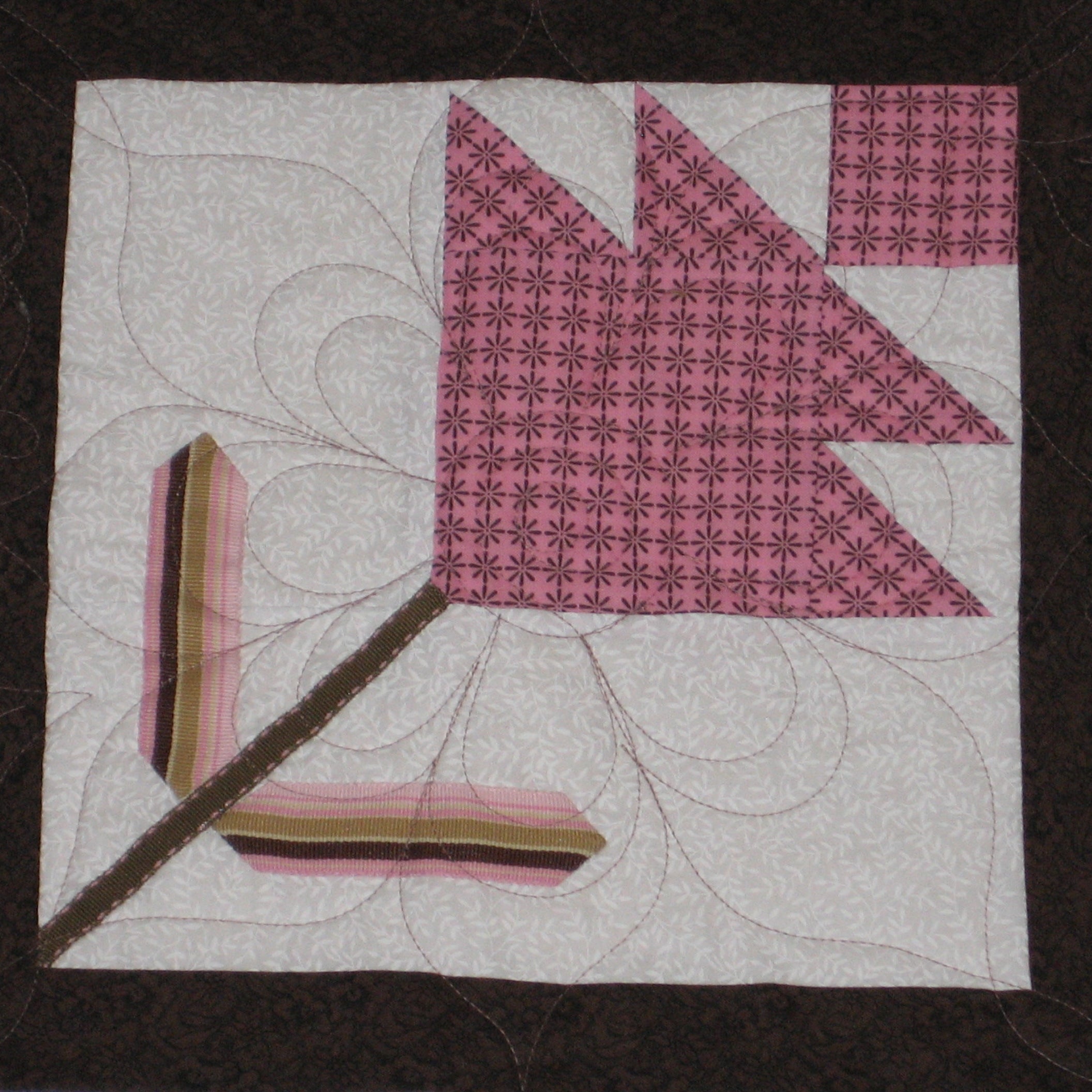 Quilt block with a flower shape in pink and brown