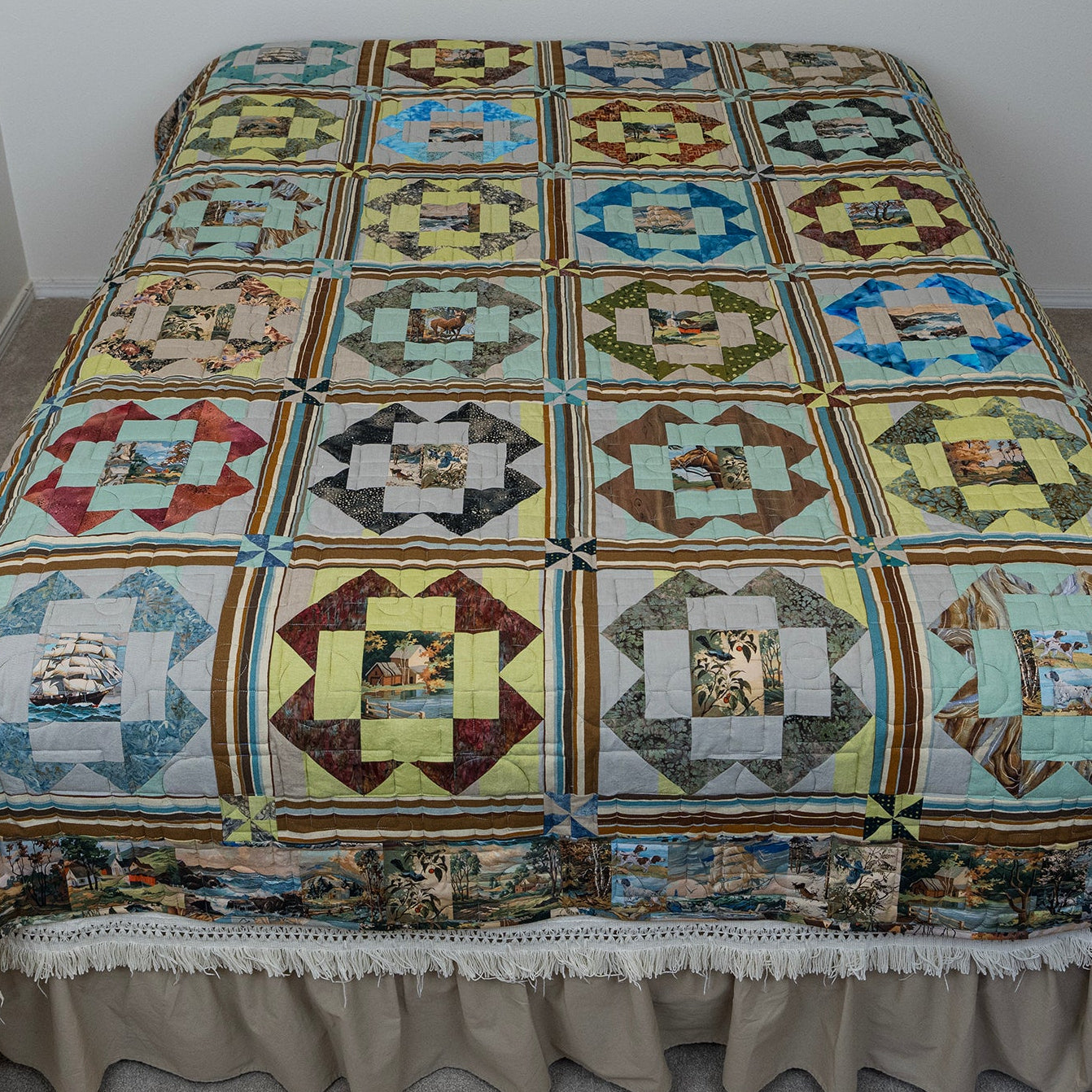 A large quilted bedspread with a matching ruffled bed skirt, featuring a patchwork design of square quilt blocks with various historical and scenic illustrations. The bedspread is displayed on a bed in a simple room with gray walls and carpet.