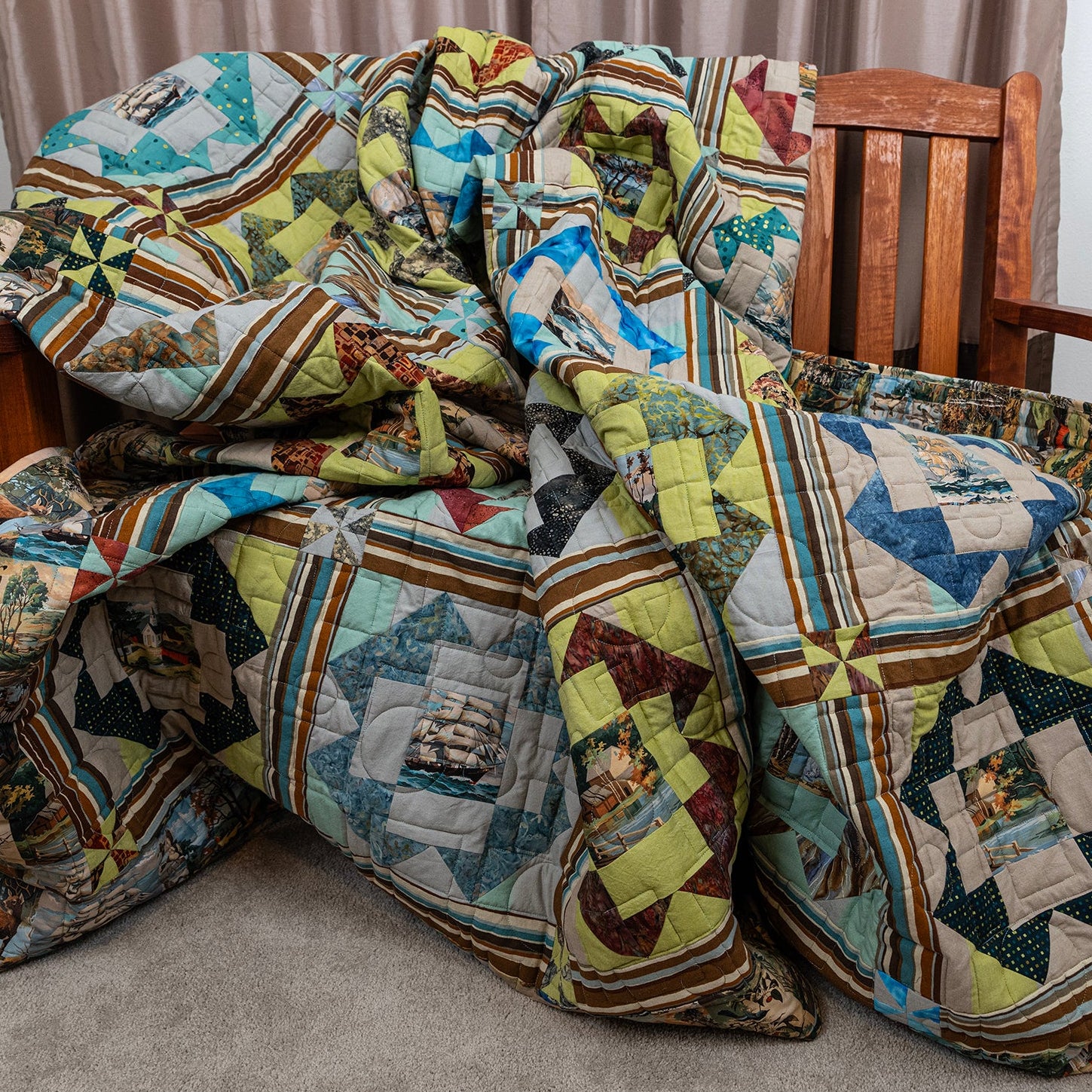 A large, multi-patterned quilted blanket with geometric and scenic patches is draped over a wooden armchair in a home setting.