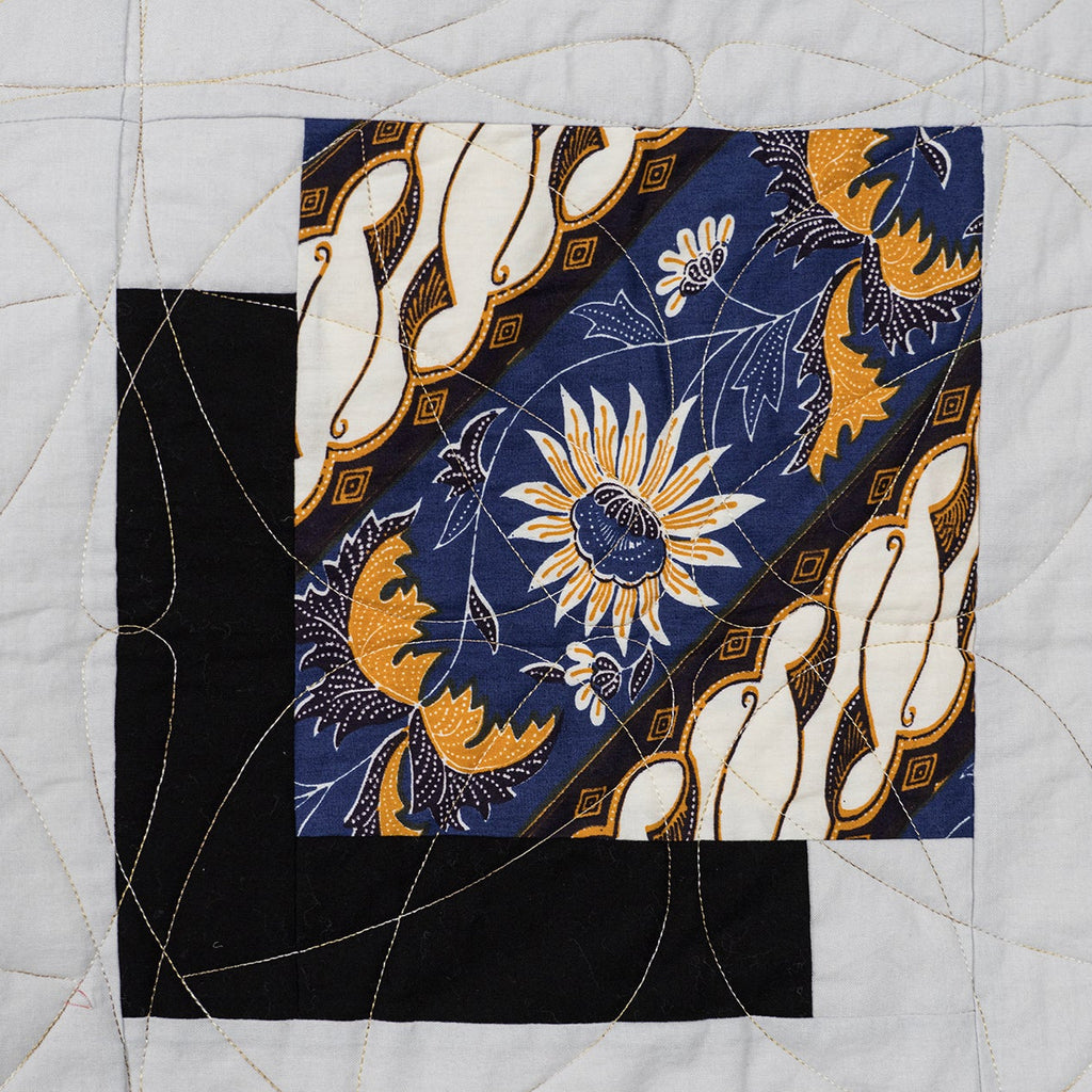Quilt block with floral and abstract patterns on a white background