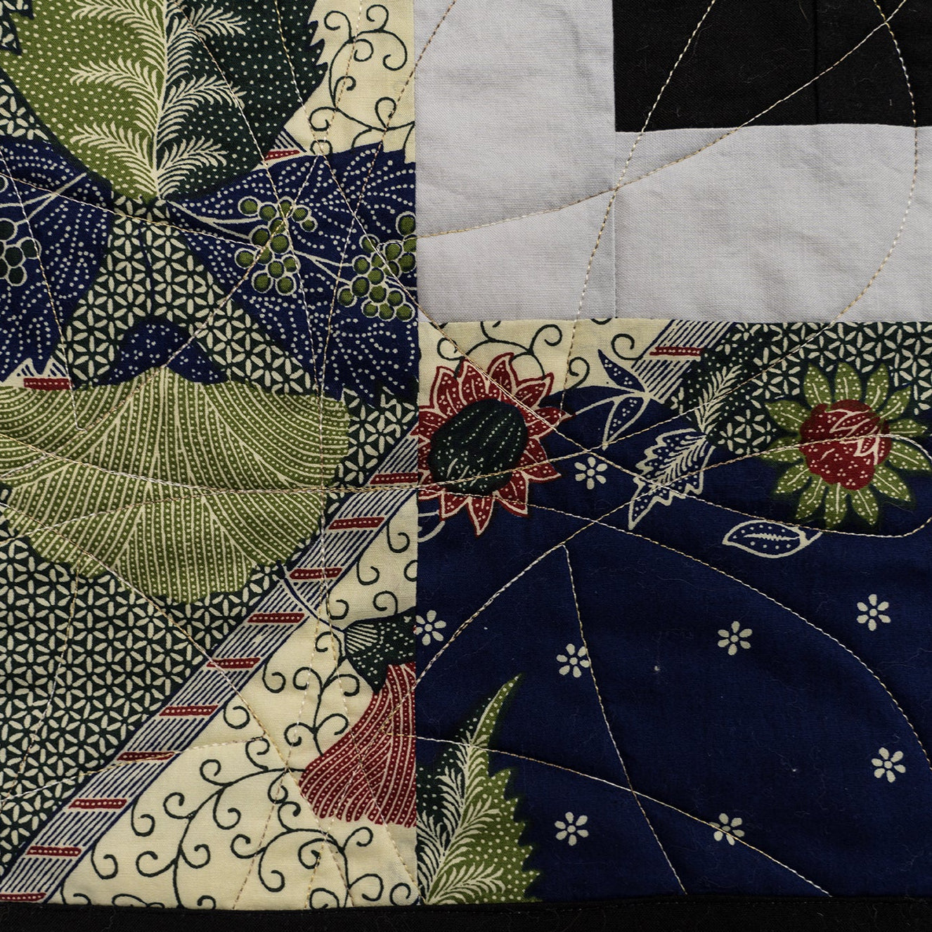 Close-up of a patchwork quilt with floral and geometric patterns.