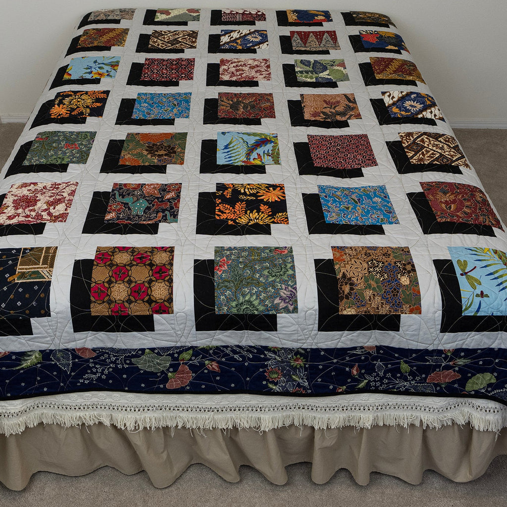Quilt with a patchwork design on a bed in a room.