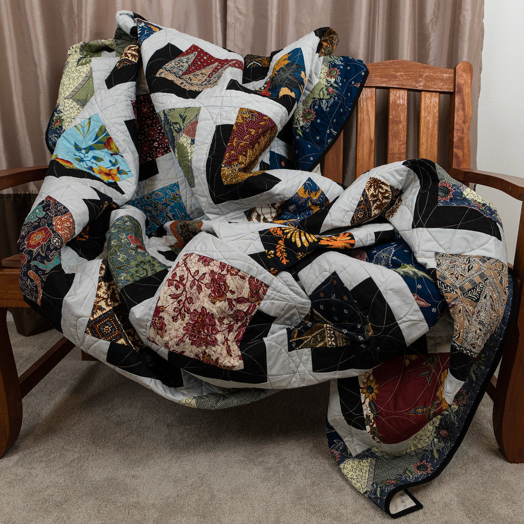 Colorful quilt draped over a wooden chair with a neutral background