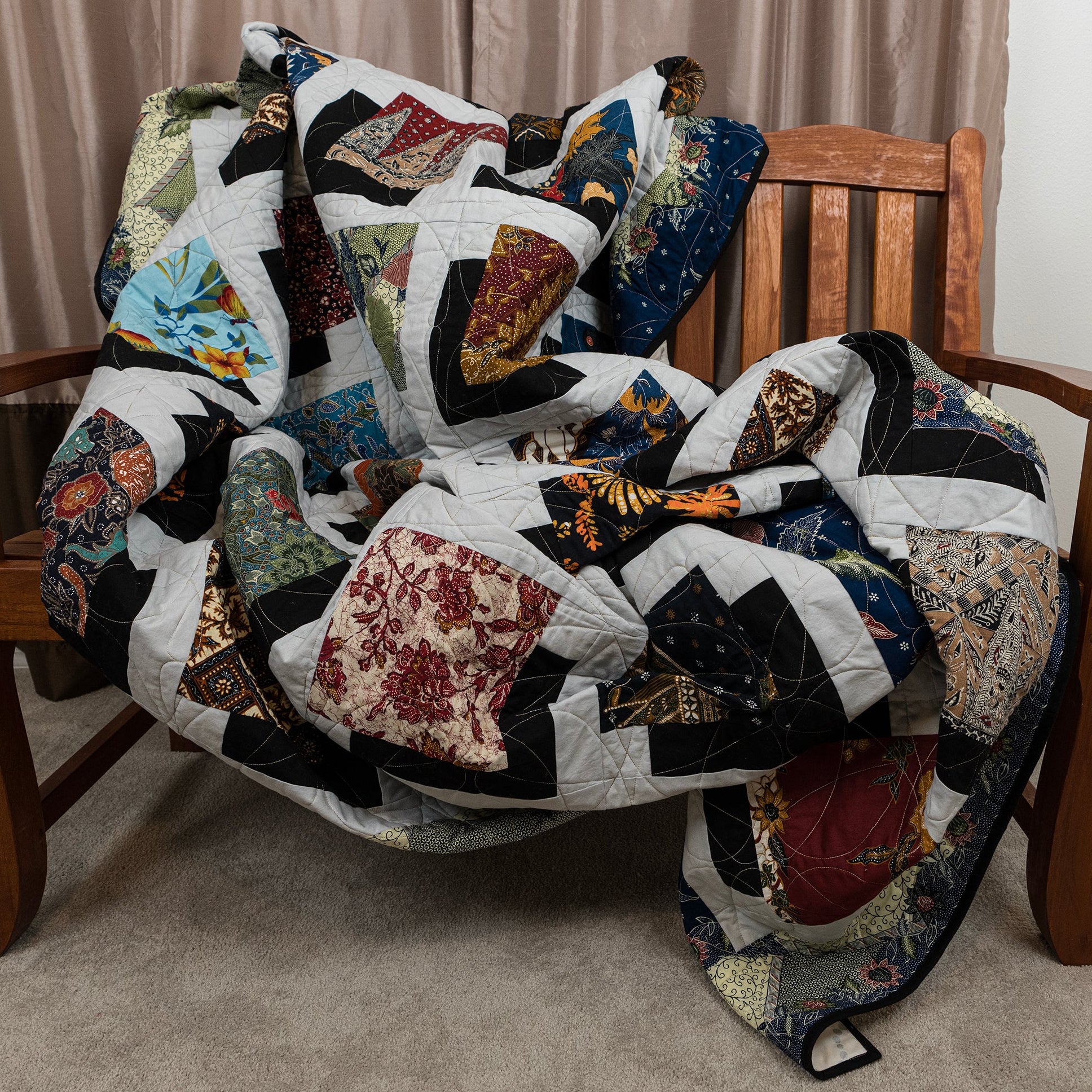 Colorful quilt draped over a wooden chair with a neutral background