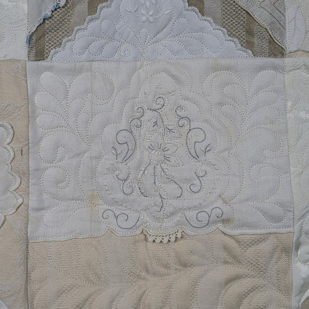 Close-up of a quilt with intricate lace and embroidery details.