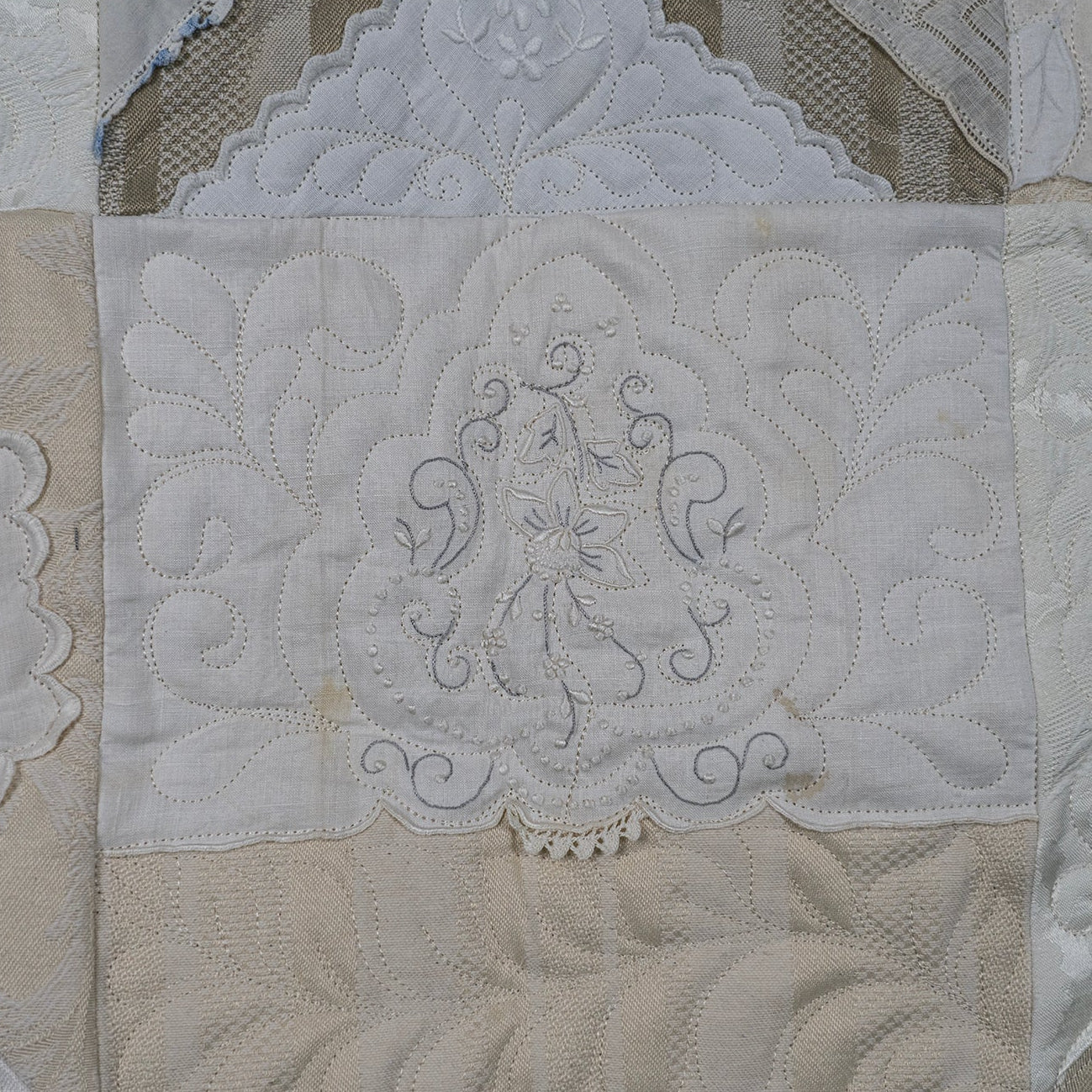 Close-up of a quilt with intricate lace and embroidery details.