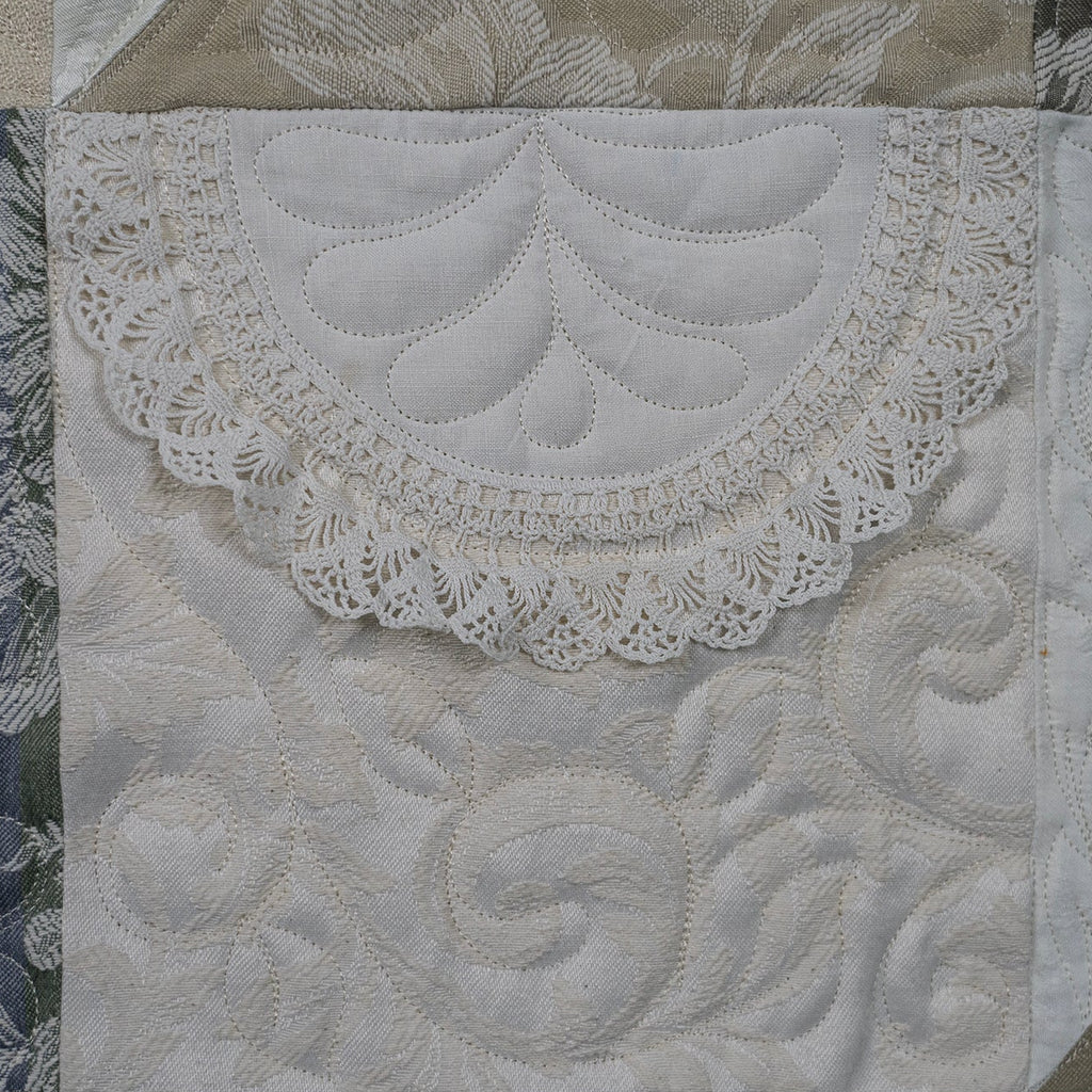 Close-up of a quilt with intricate lace and embroidery details