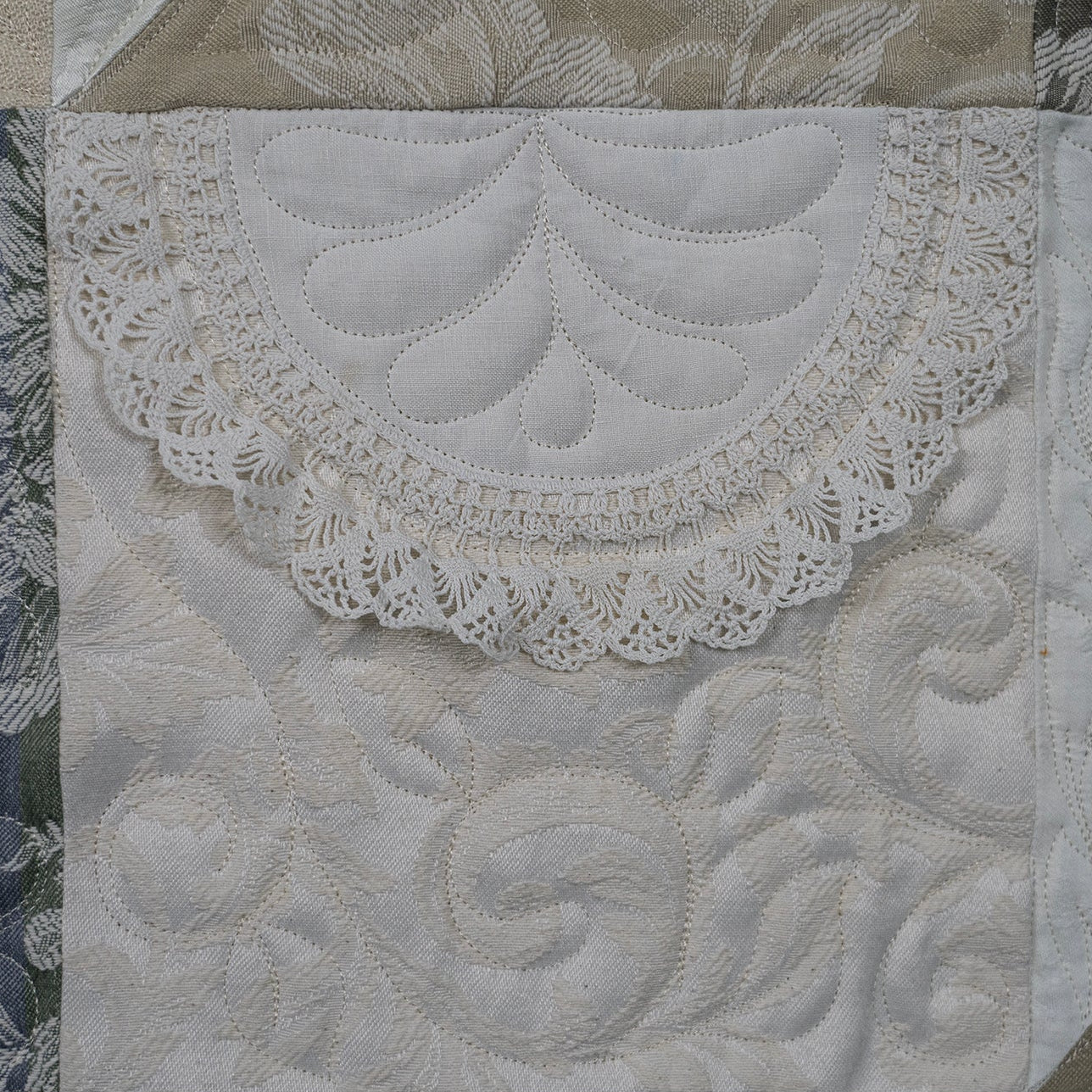Close-up of a quilt with intricate lace and embroidery details