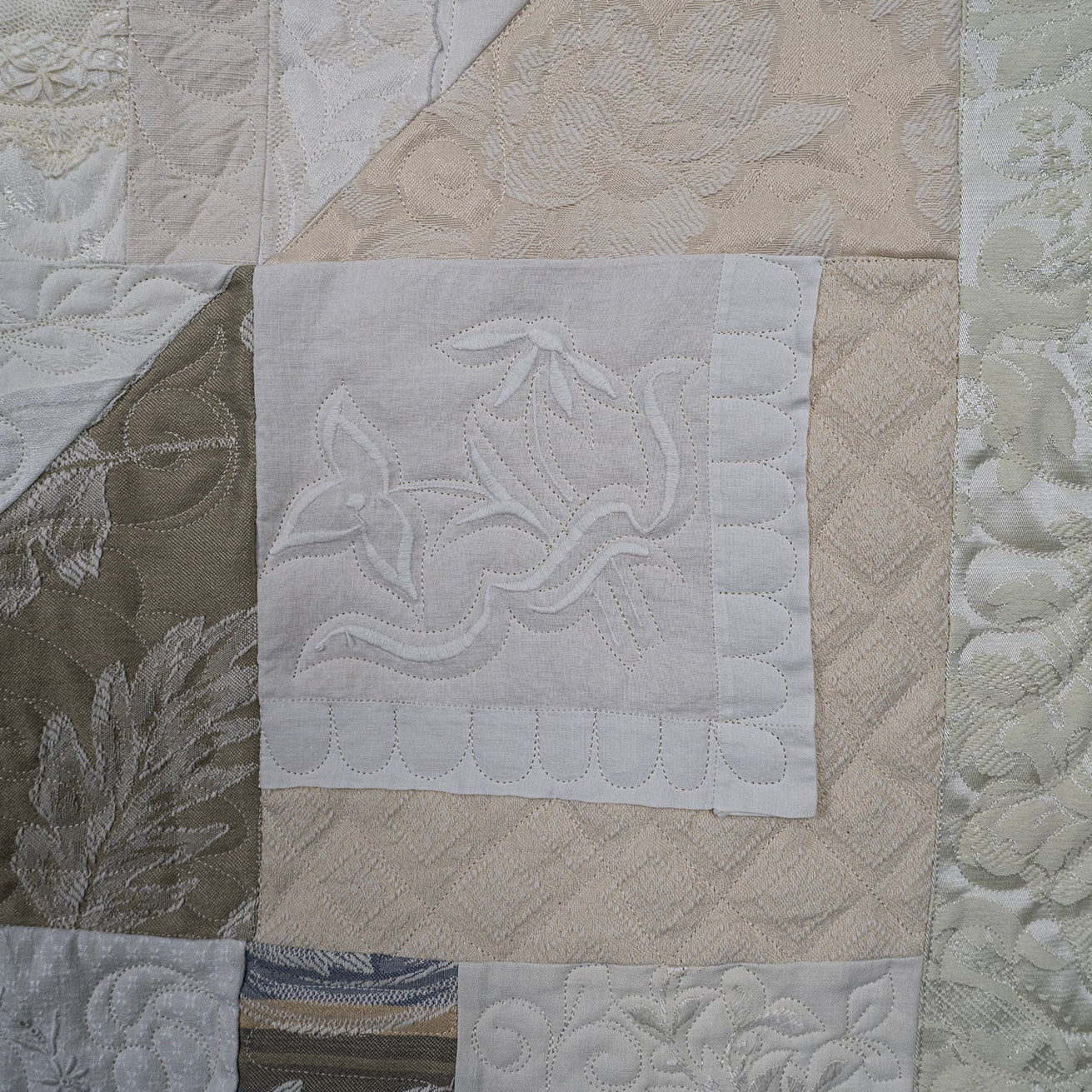Close-up of a quilt with floral patterns and a central white square with a design.