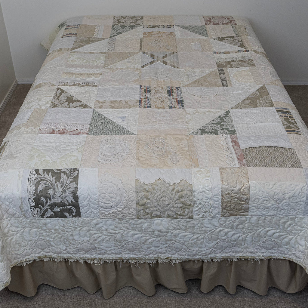 Patchwork quilt on a bed in a room with plain walls.