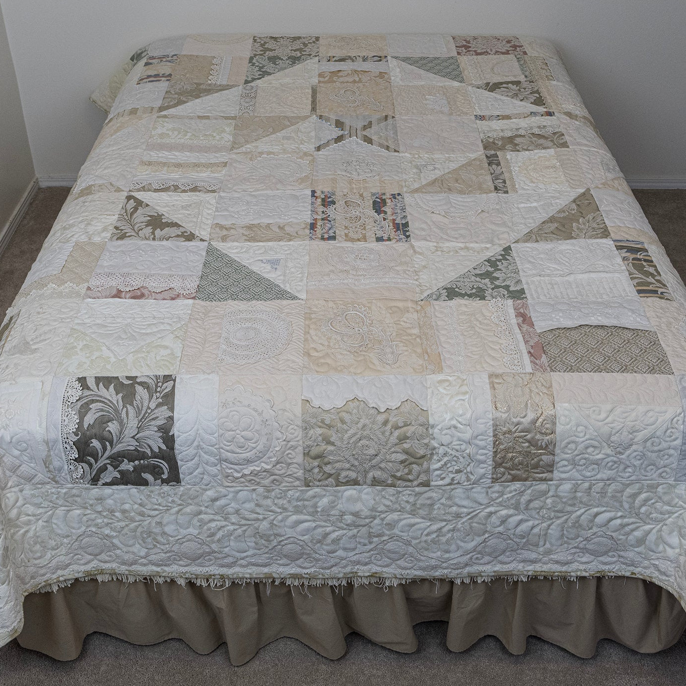 Patchwork quilt on a bed in a room with plain walls.