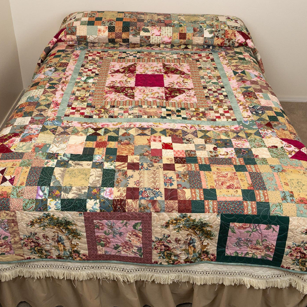 A large patchwork quilt with a ruffled beige bed skirt, shown on a bed in a bedroom setting with beige walls and carpet.