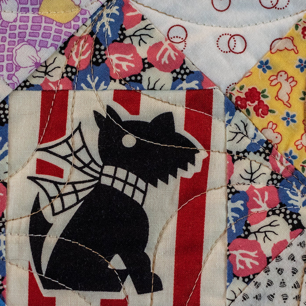 Quilted fabric with a black dog silhouette on a colorful patchwork background