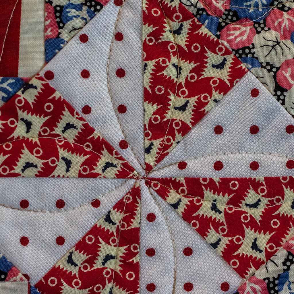 Quilt block with red, white, and blue patterns featuring stars and polka dots.