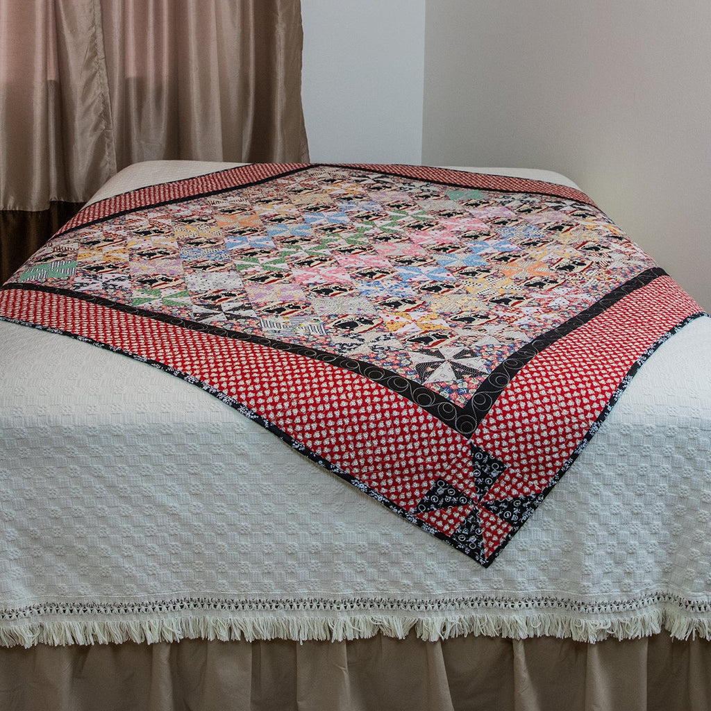 Quilted blanket with intricate patterns draped over a bed in a room.