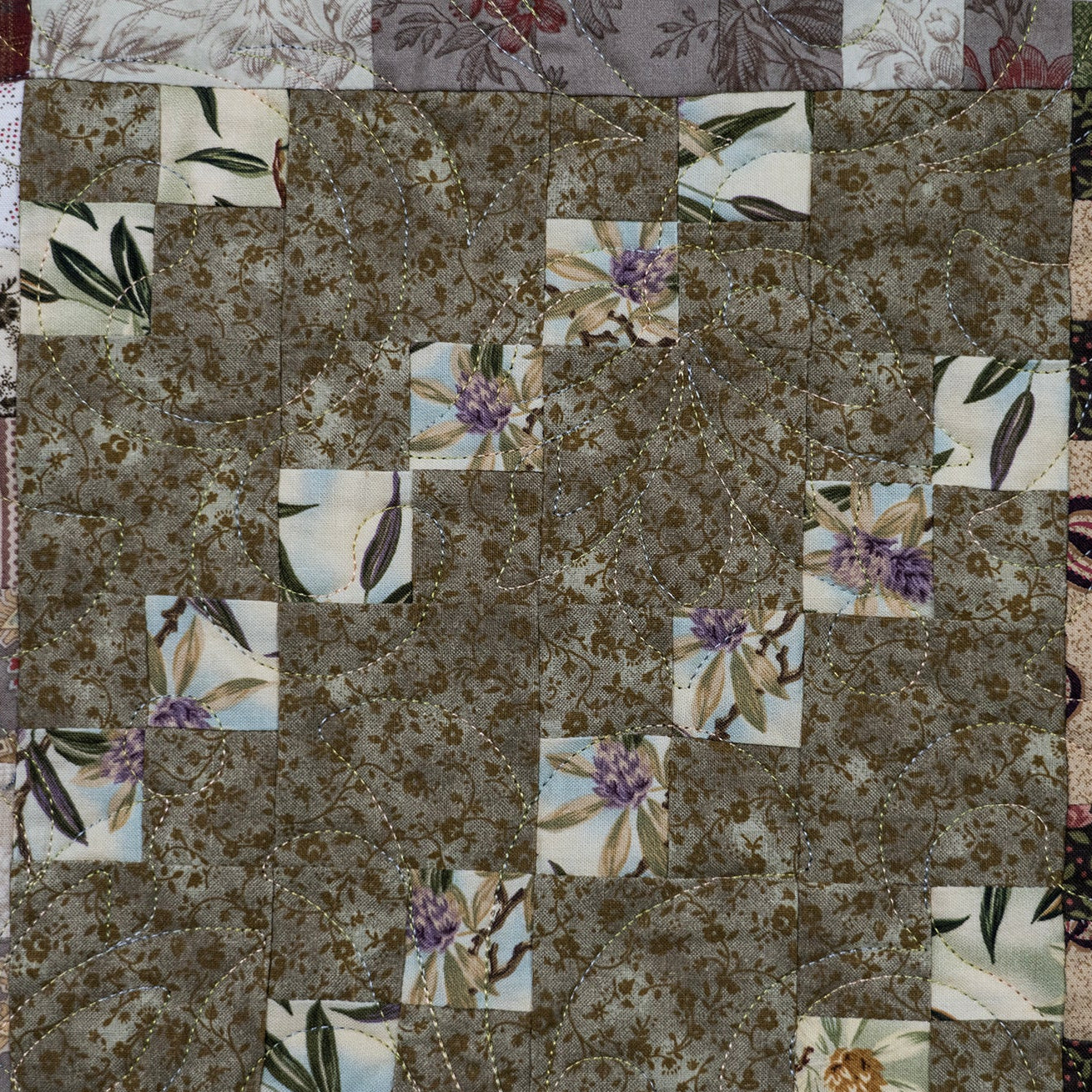 Patchwork quilt with floral patterns on a textured fabric background