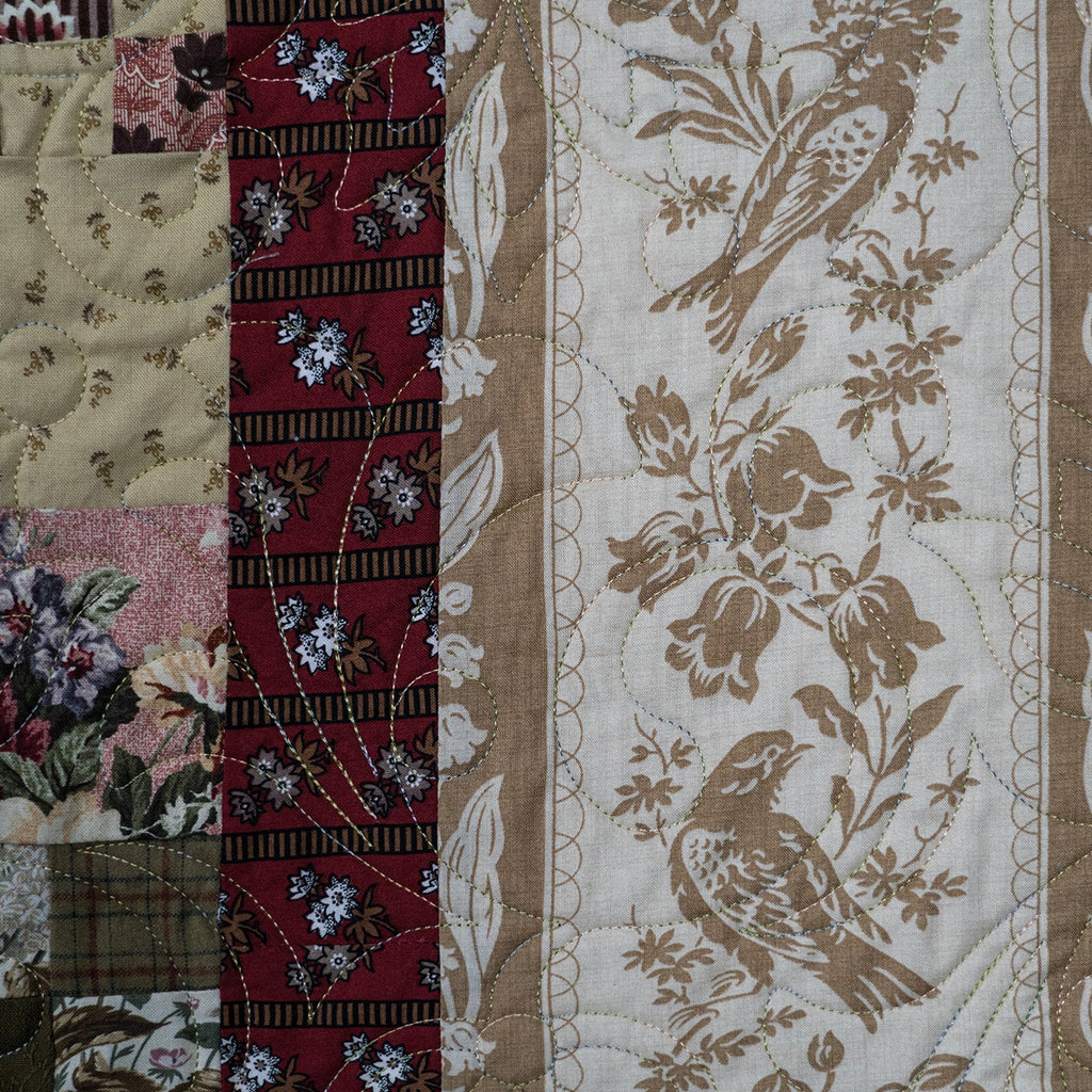 Quilt with floral and bird patterns in a patchwork design.