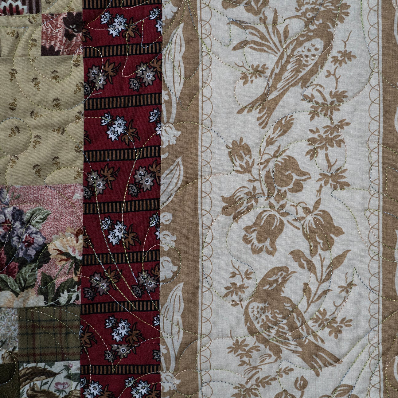 Quilt with floral and bird patterns in a patchwork design.