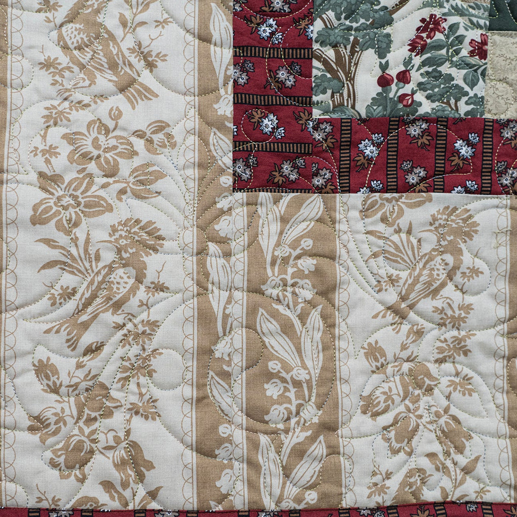 Quilt with floral and bird patterns in beige, red, and green.
