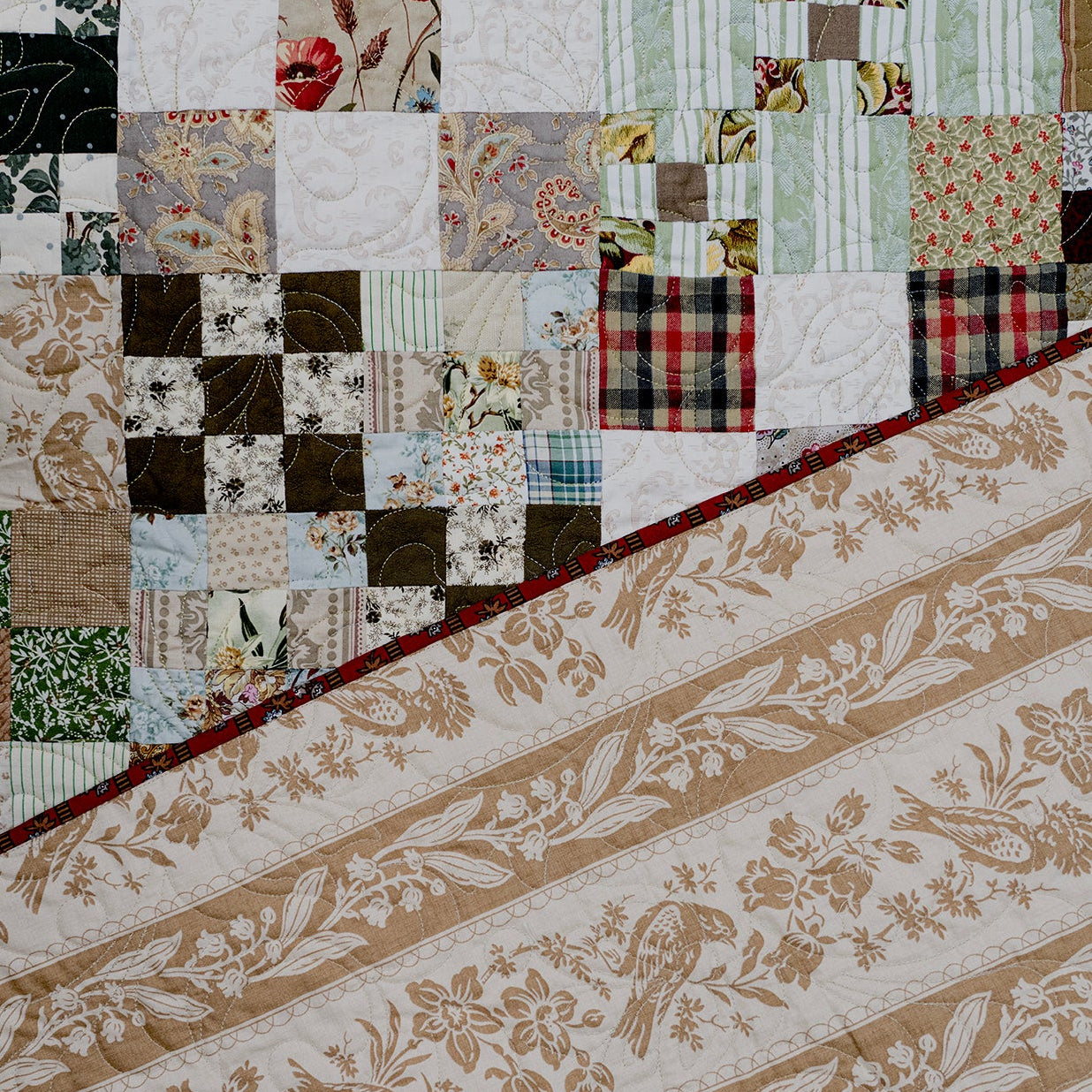 Patchwork quilt with various patterns and colors on a floral fabric background