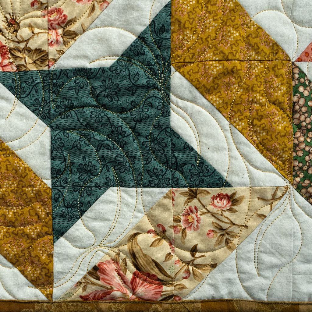 Quilt with geometric pattern featuring various fabrics and colors