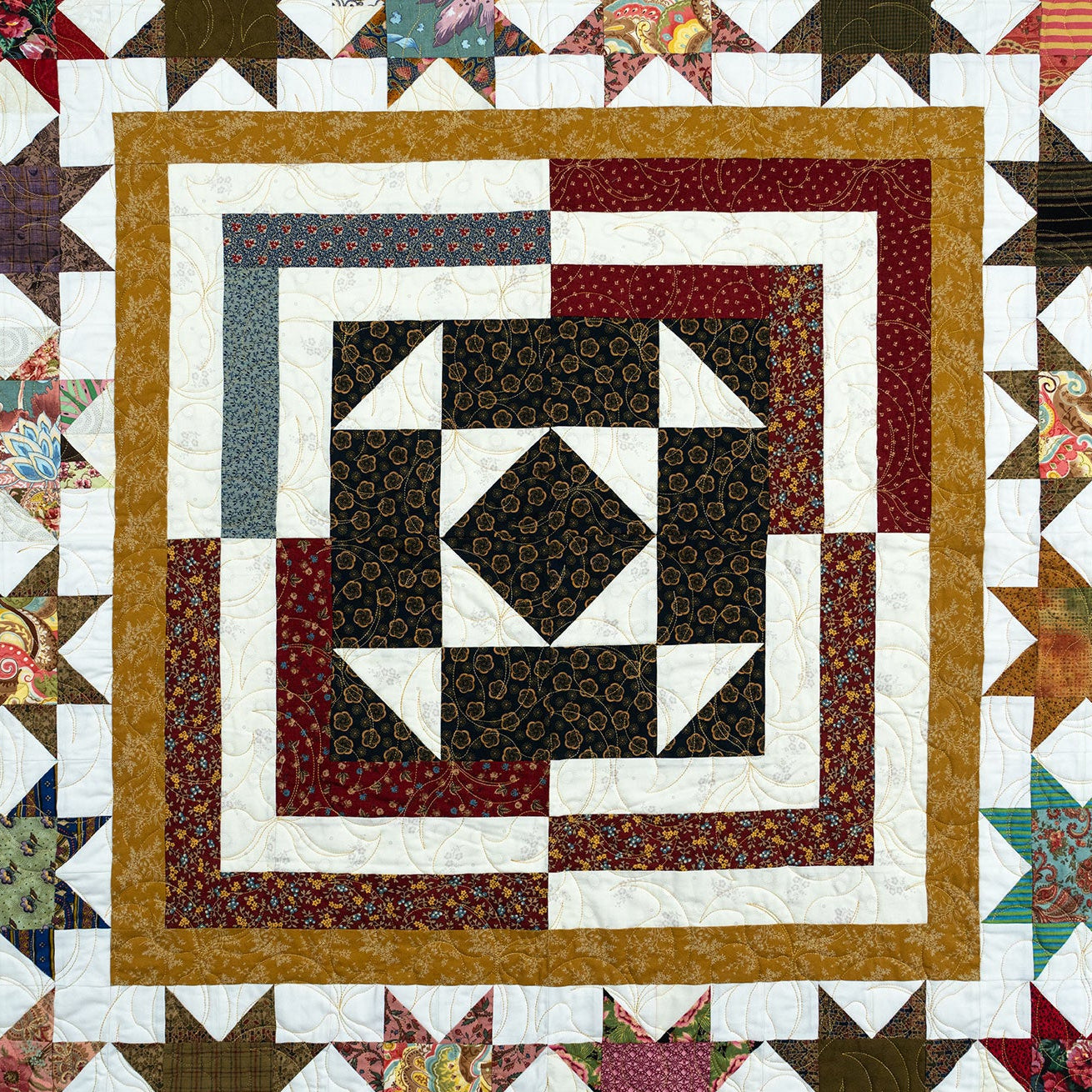 Quilt with geometric pattern featuring a central diamond shape surrounded by concentric squares and stars.