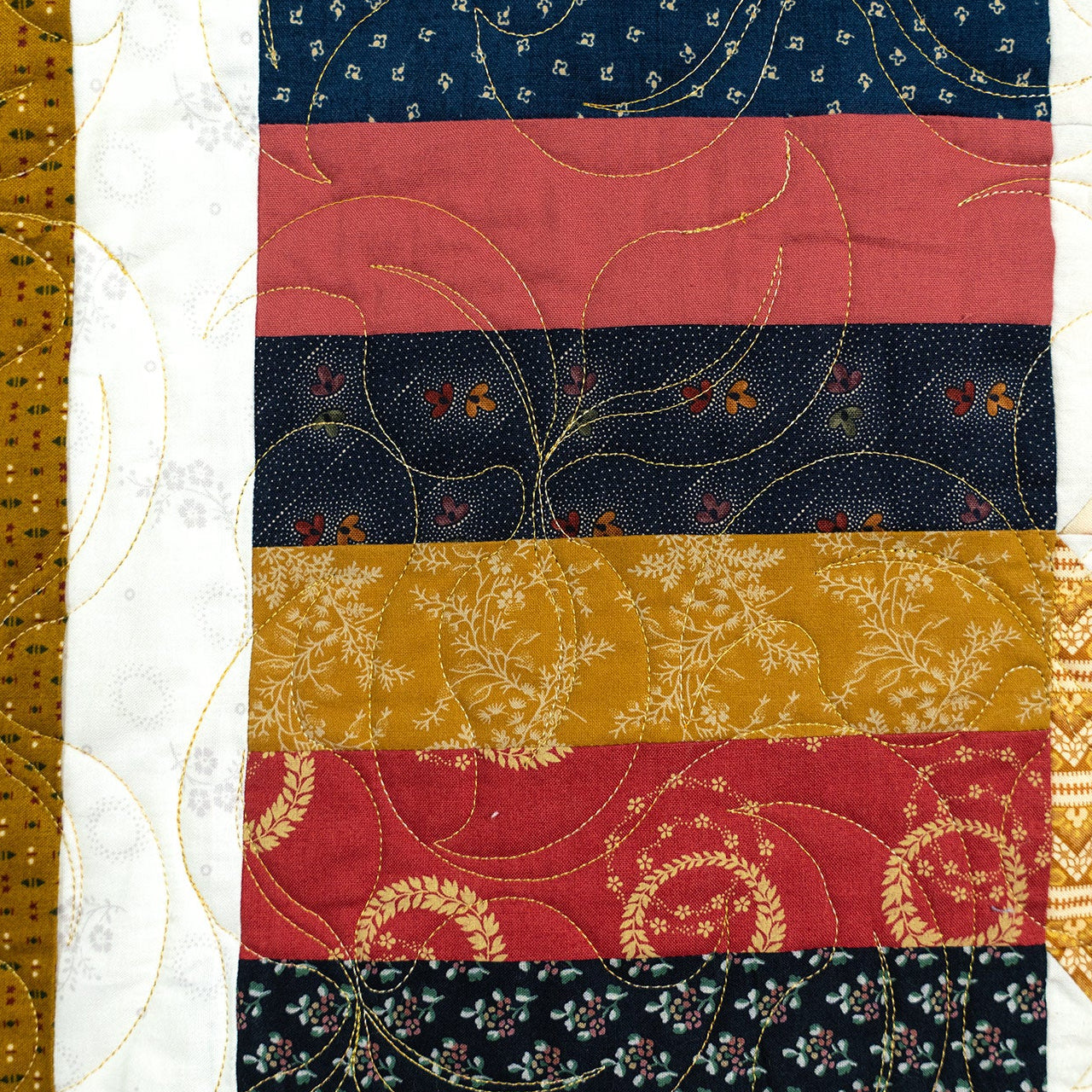 Quilt block with red, blue, and gold patterns on a white background