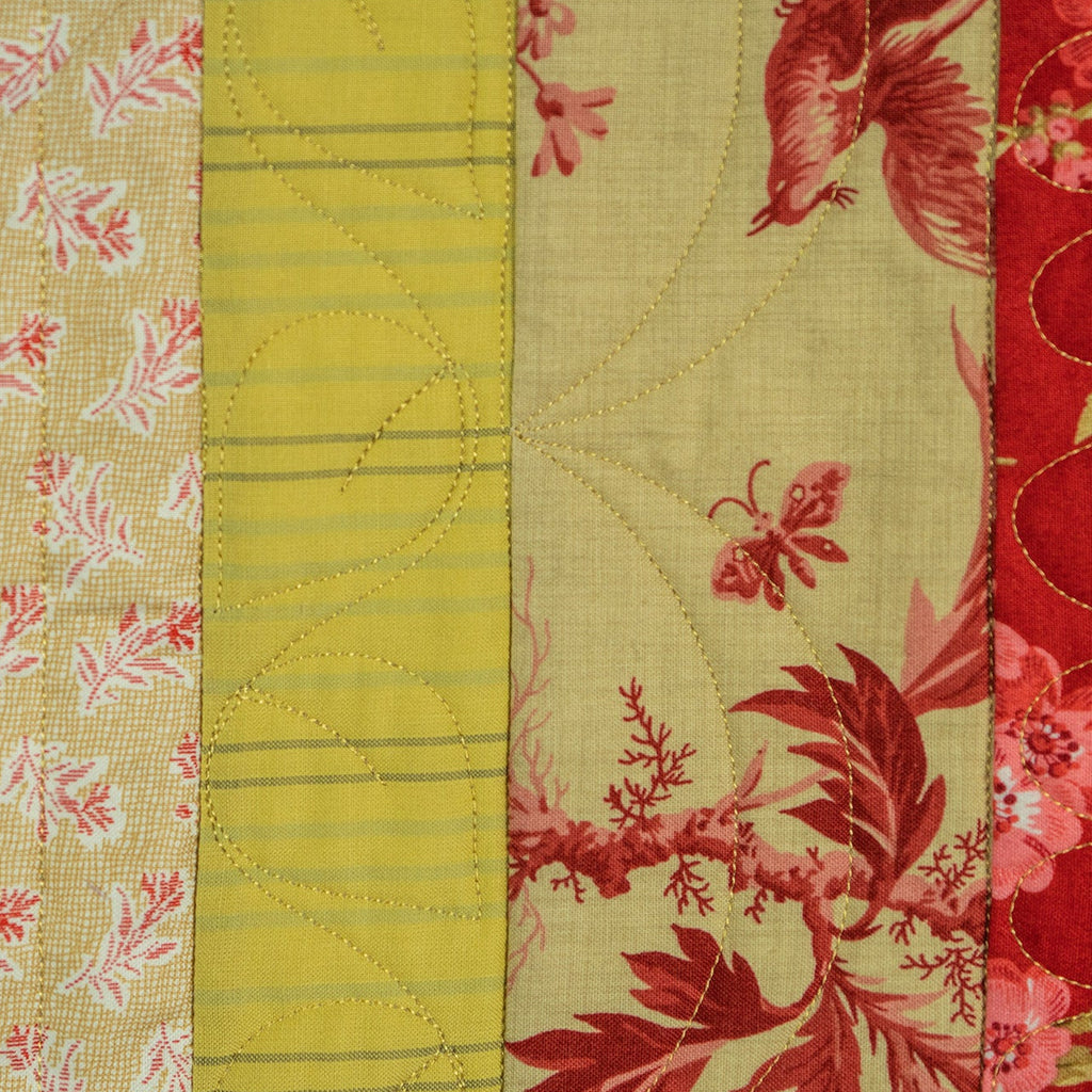 Patchwork fabric with floral and geometric patterns in red, yellow, and pink.