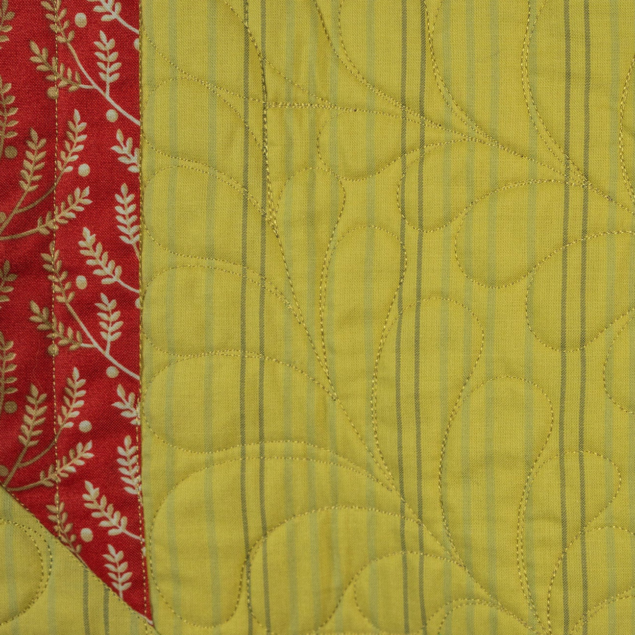 Quilted fabric with a yellow pattern, red fabric with white floral patterns, and beige fabric with pink floral patterns.