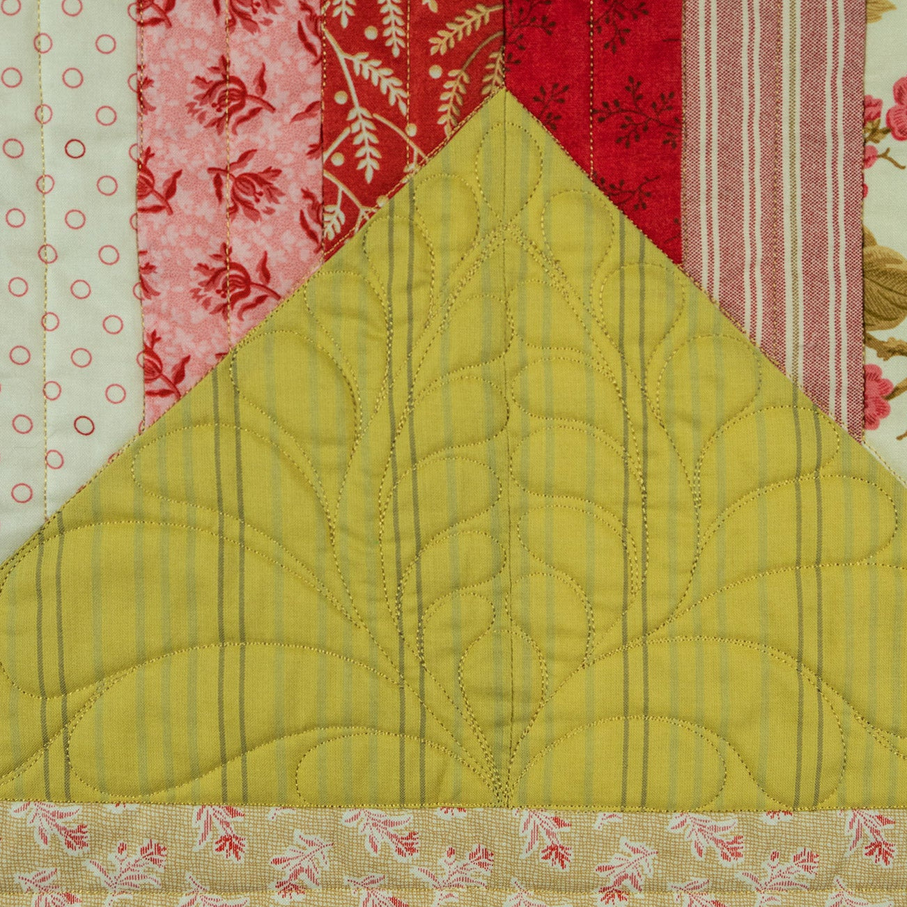 Quilted fabric with a yellow triangle and floral patterns in the background