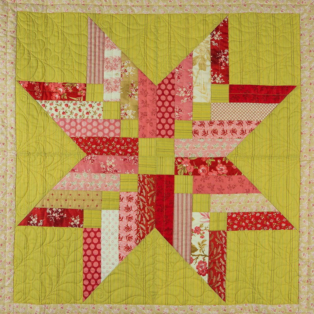 Patchwork quilt with a star design in red, green, and pink on a beige background