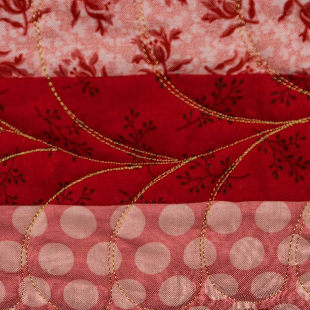 Stack of red, gold, and pink patterned fabrics