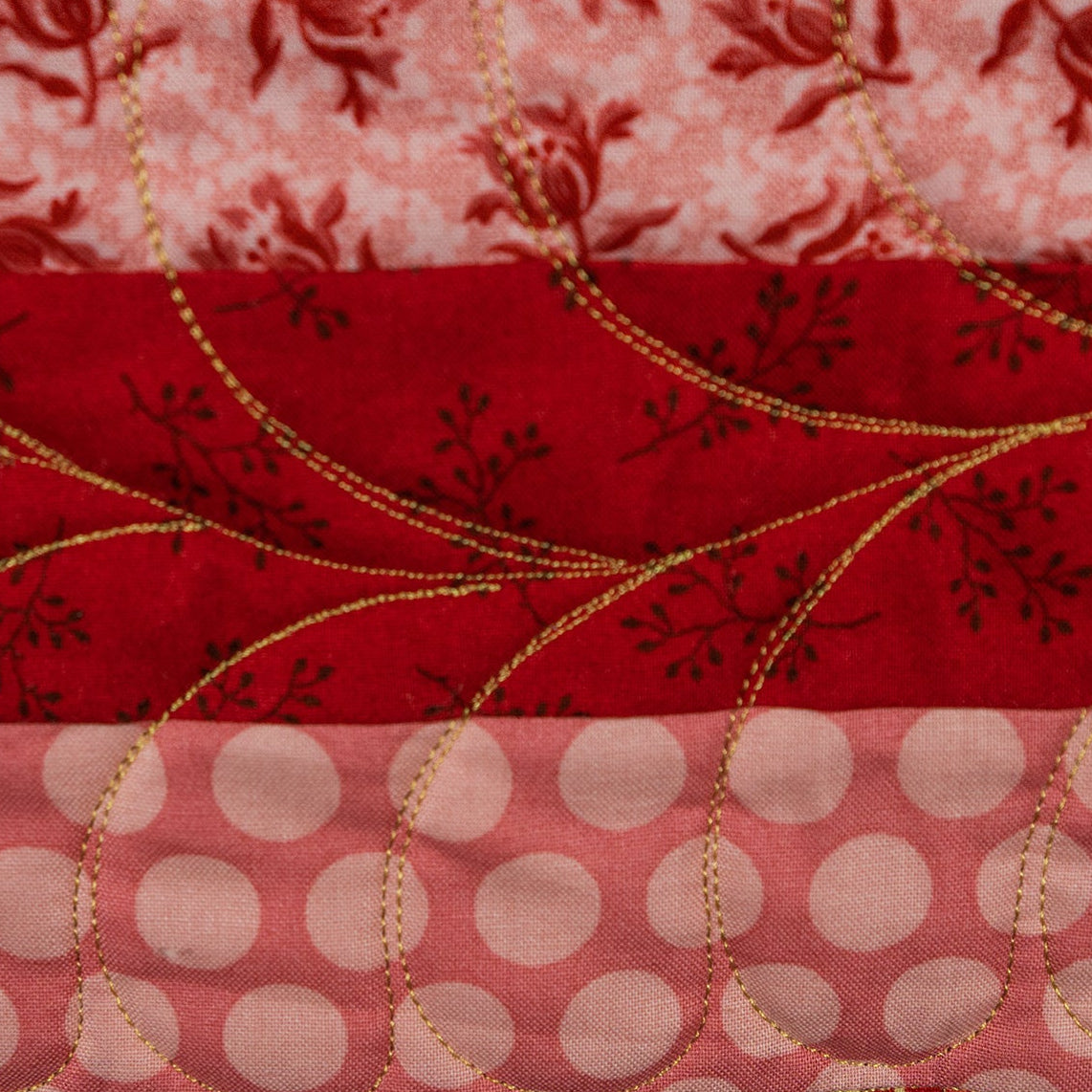 Stack of red, gold, and pink patterned fabrics