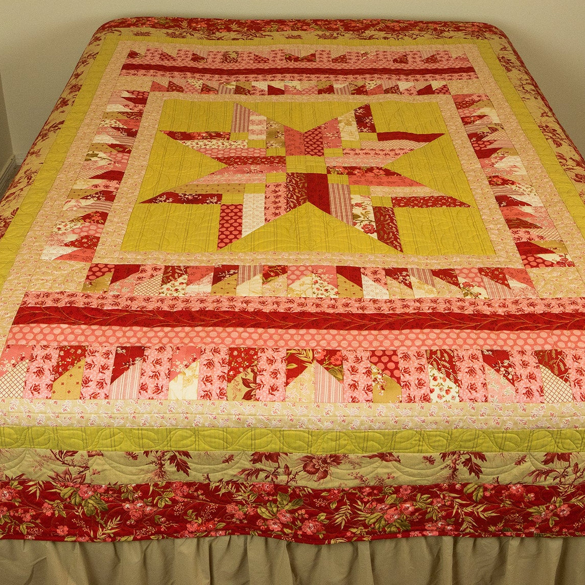 Quilt with star pattern on a bed against a plain wall