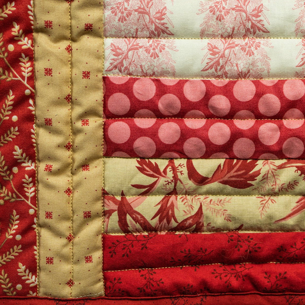 Quilted fabric patchwork with red, pink, and beige patterns