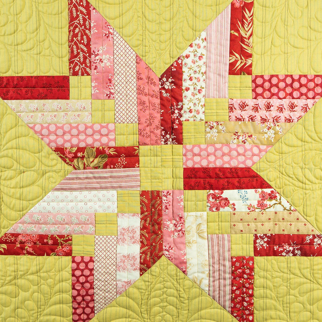 Quilt with a star pattern featuring red, pink, and yellow colors on a yellow background.