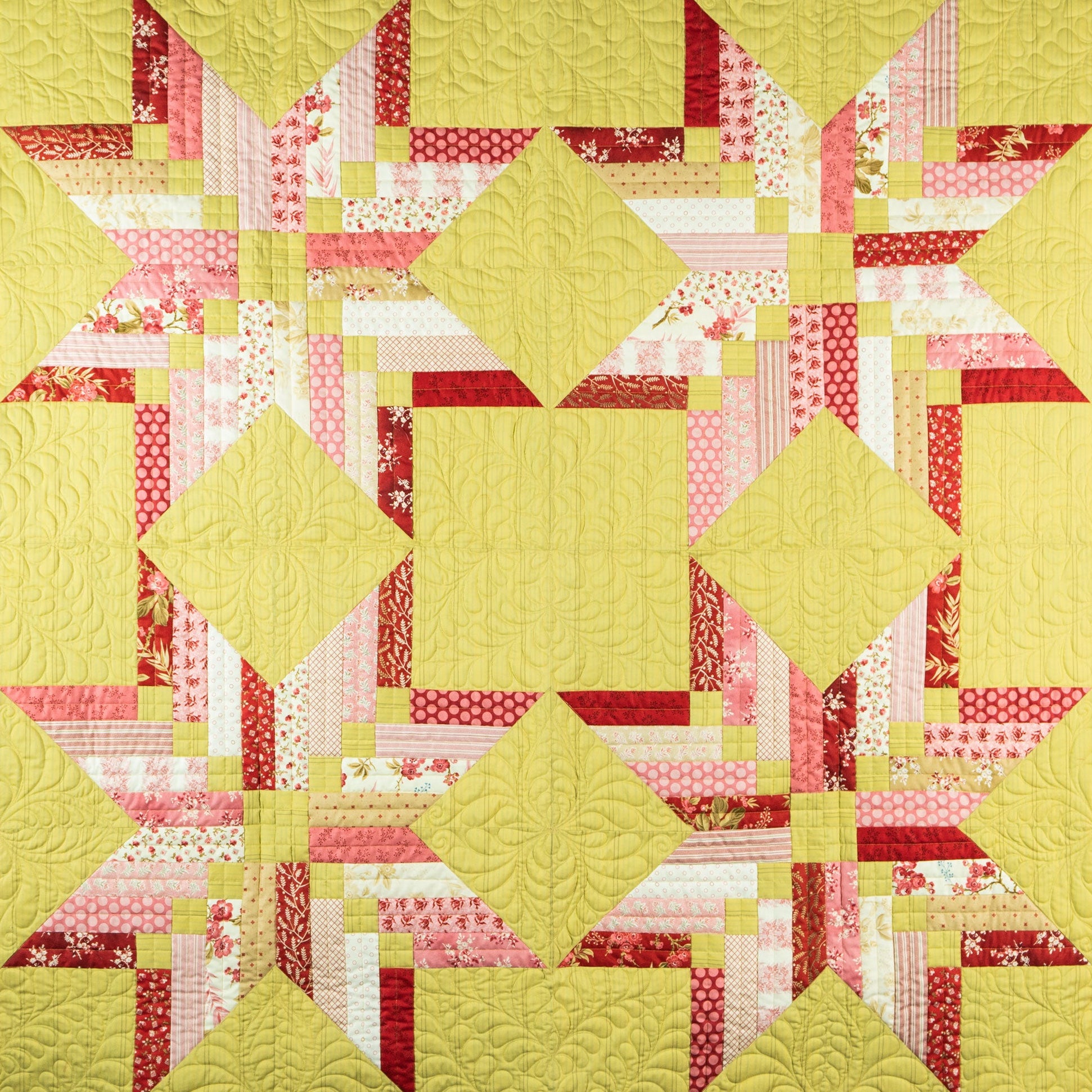 Quilt with star pattern featuring yellow, pink, and red colors on a yellow background