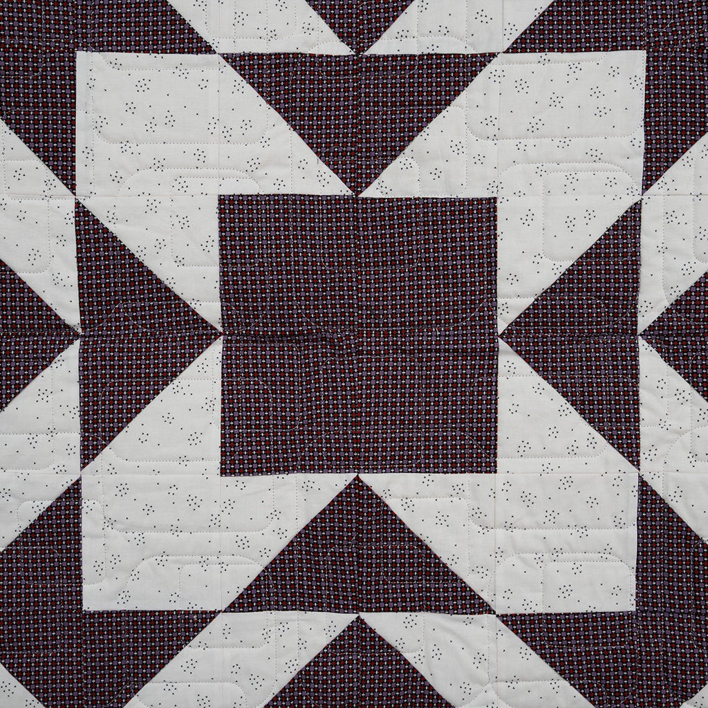 Quilt with geometric pattern of squares and triangles on a dark background