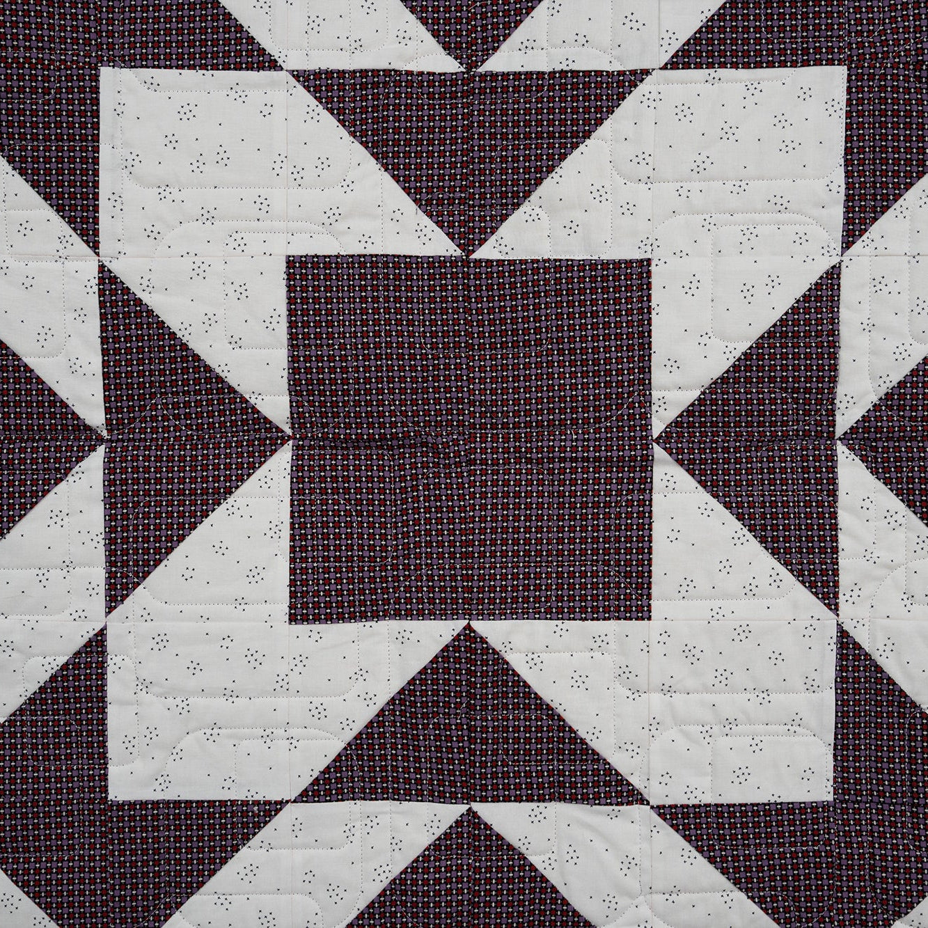 Quilt with geometric pattern of squares and triangles on a dark background