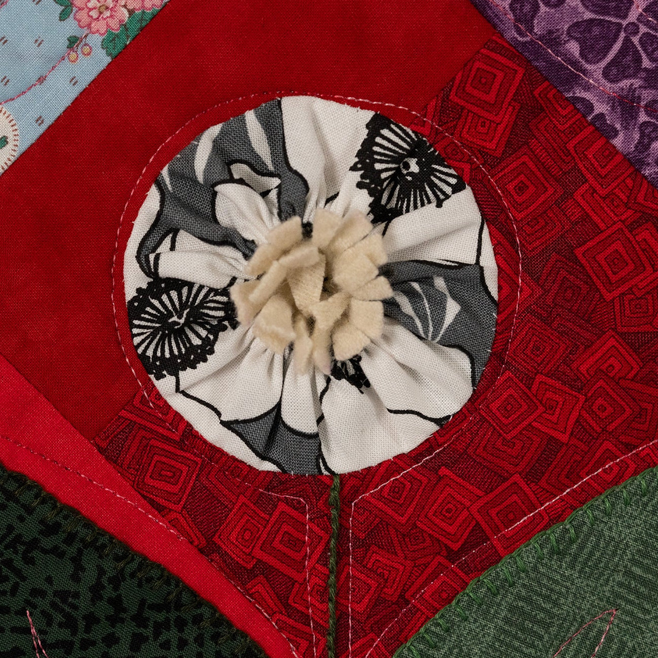 Quilted fabric block with red border and central floral design
