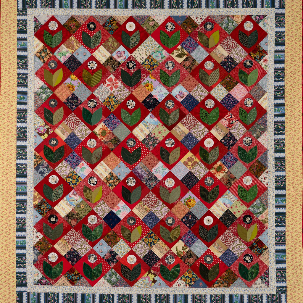 Quilt with a diamond pattern featuring a floral shape in various colors and textures.
