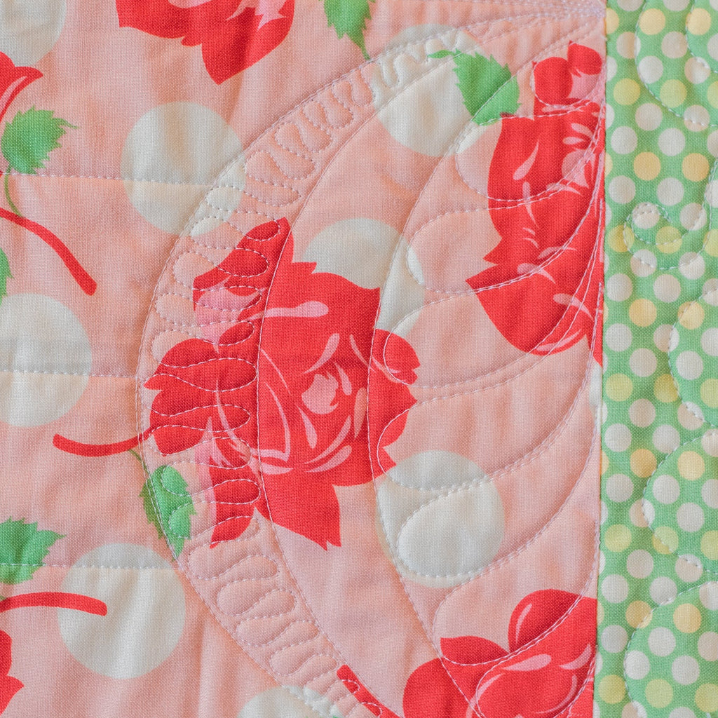 Quilt with floral and polka dot patterns on a pink background