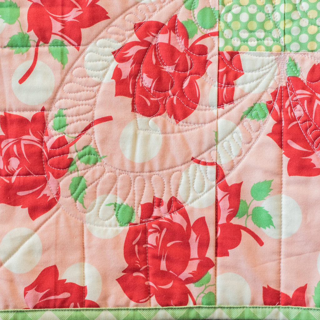 Quilt with red floral pattern on a pink background