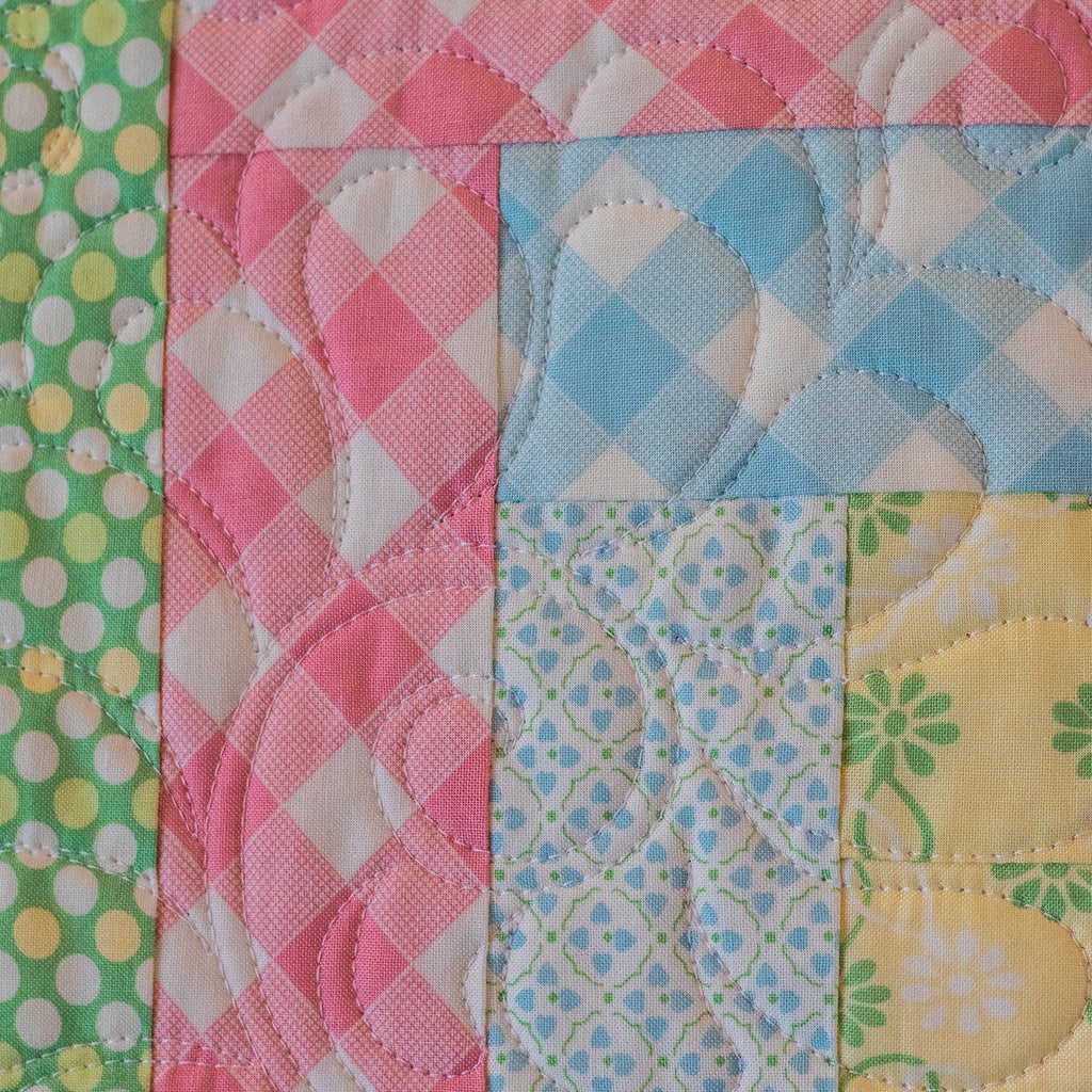 Patchwork quilt with colorful patterns in pink, blue, green, and yellow.